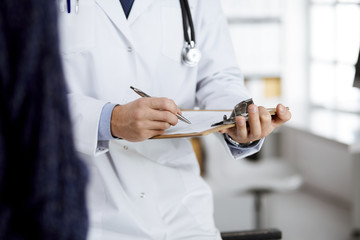 Female doctor and male patient discussing current health examination while sitting in clinic, close-up. Medicine concept