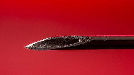 needle tip of an injection syringe, macro shot, on red background