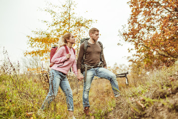 Fototapeta premium Tourists wading through the hills holding hands. A young couple of people in love checks the strength of their relationship while traveling in the wild. Hiking concept