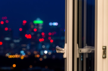 An open window against a blurry Canary Wharf London night skyline