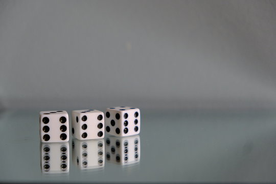 Three Dice showing triple sixes. Rolling dice. Taking chances. Three numbers rolled.