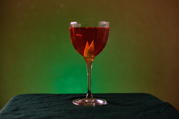 red cocktail in nick and nora glass on green background