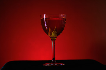 red cocktail in nick and nora glass on red background