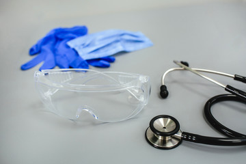 Gloves, mask, glasses and stethoscope for a doctor on a gray background top view side view