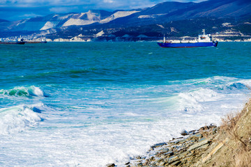 Emerald storm waves in snow-white foam break on the shore. The coast is strewn with yellowish...