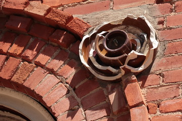Broken Porcelain electric insulator on the side of a red brick building