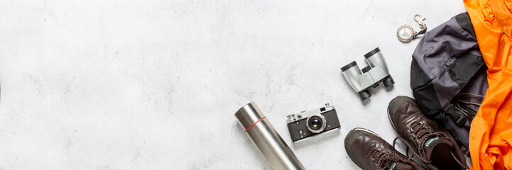 Travel backpack, compass, boots, thermos, jacket, camera and binoculars on a white background. Concept of hiking, tourism, camp, mountains, forest. Banner. Flat lay, top view