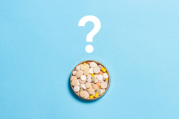 Pills and question mark on a blue background. Insomnia, a choice of drugs, vitamins. Flat lay, top view