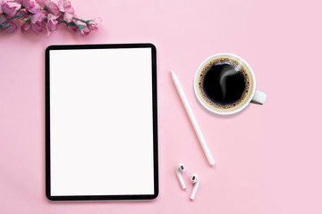Modern tablet, white wireless headphones with coffee on a pink background.