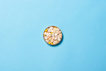 Bowl with pills of different types on a blue background. The concept of insomnia, vitamins. Flat lay, top view
