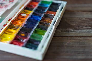 Set of watercolor paints and paintbrushes for painting closeup. Selective focus. wooden background. Copy space