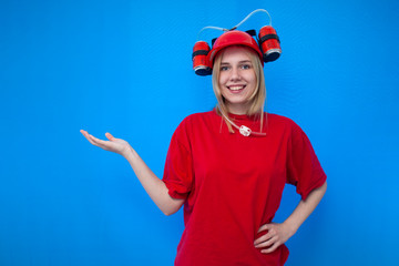 young happy girl fan holds a place for text with his hand and smiles, cheerleader on a blue background