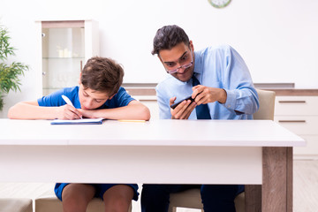 Obraz premium Busy father helping his son to prepare for exam