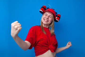 happy girl fan in red uniform rejoices victory on a blue background, a cheerleader with a beer hat shows victory gesture
