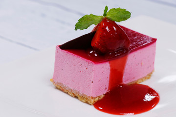 strawberry cheese cake in a white plate with raspbery sauce