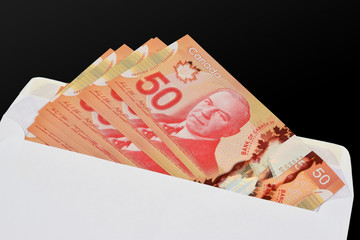 An illustrative concept image of $50 (Fifty) Canadian dollar (CAD) banknotes in a white envelope to...