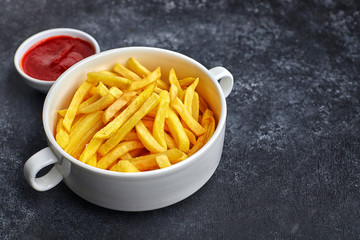French fries with barbecue sauce, in a white bowl, against a dark background with place for text.