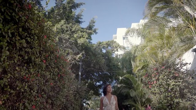 Beautiful woman walks down path leading to colorful and vibrant umbrellas hanging from ceiling while on vacation