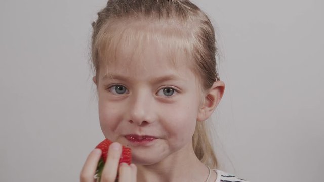 little caucasian girl eats ripe red strawberries