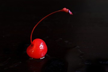 Isolated Maraschino cherry against a black background.
