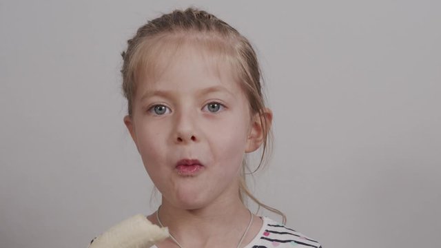 little caucasian girl eats ripe banana