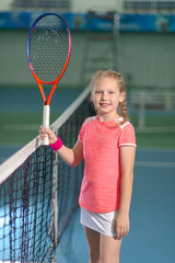 A girl plays tennis on an indoor tennis court.