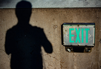 Shadow of a man and an fire exit sign on concrete wall
