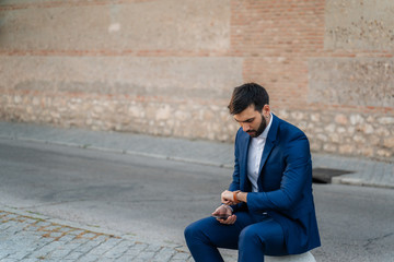 Fototapeta na wymiar Young business man with white shirt and suit in outdoor city looking at watch
