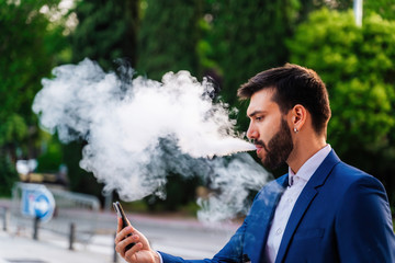 Young business man with white shirt and tie in outdoor city looking at phone