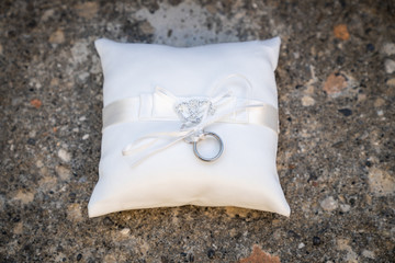 Anelli di matrimonio su cuscinetto bianco. Sfondo in pietra.