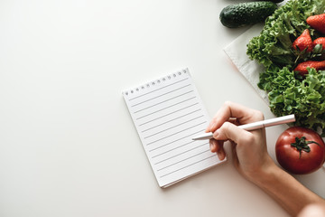 Woman makes notes in a notebook, food shopping list or writing recipes. Mock up. Flat lay