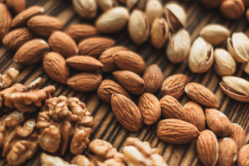 Different types of nuts, nut mix of almonds, hazelnuts, cashews, peanuts on a wooden board. Close up