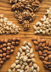 Different types of nuts, nut mix of almonds, hazelnuts, cashews, peanuts on a wooden board. Close up