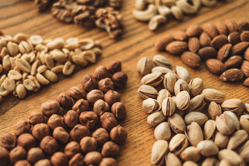 Different types of nuts, nut mix of almonds, hazelnuts, cashews, peanuts on a wooden board. Close up