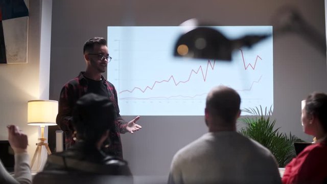 Business meeting. Office Team Analyzes Business Growth. Young Man Interested In Audience. On Screen Growth Graph Monitor