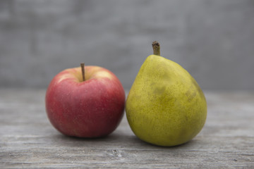 red apple and yellow pear on a wooden table