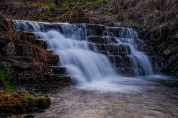 Fototapeta na wymiar Waterfall Zalotomyatyi at the Zalotomyatyi river in carpatian mountains and green forest. National park Skolivski Beskidy. April 2020