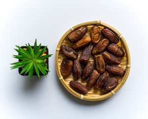 Dates or kurma on white background with flower pot, the favorite food of the holy ramadhan month.
