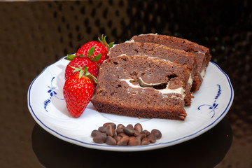 Brownie coffee cake decorated with fresh strawberries on a black matte background.
