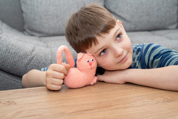 Cute child blond boy in casual clothes playing with handmade toy.