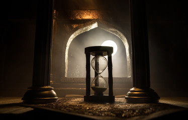 Silhouette of hourglass inside room. Abstract surreal idea with empty space. Selective focus