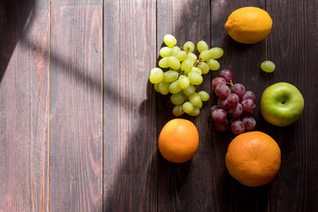 fruits on a wooden table on the right side. apple, orange, grapefruit, lemon, grape. place for text. wood background. view from above