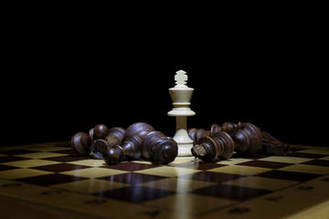 King winner stands and other chess 
 pieces lie on a chessboard on a black background. the king...