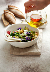 fresh summer salad of arugula, avocado, radish and strawberries and edible flowers, olive oil.