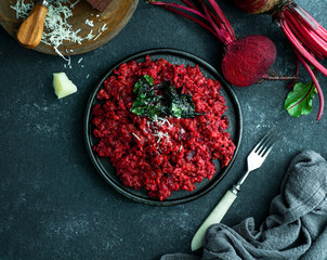 beetroot risotto with hard cheese, caramelized leaves,  dark black background