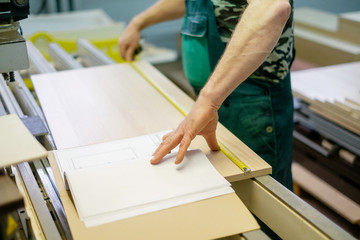 Close-up hands of cabinet maker using the tape measure. Wooden furniture production. Joinery.