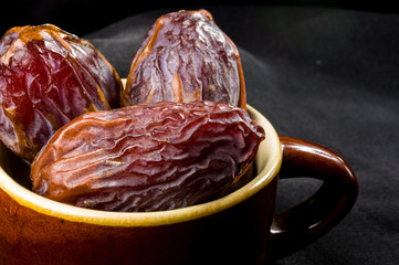 Big luxury dried date fruit in bowls on the dark surface, kurma ramadan kareem concept, close up.