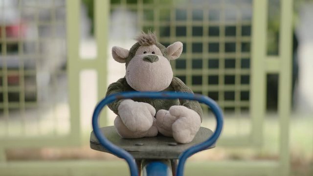 A Monkey Toy rocking on a Park Seesaw. 