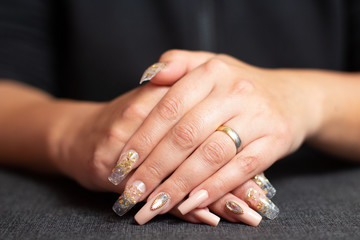 Obraz na płótnie Canvas Manicure golden nails with diamonds on a grey background