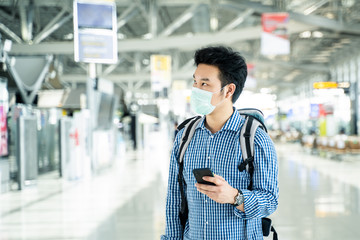 Asian traveler man wearing face mask in departure terminal in airport.